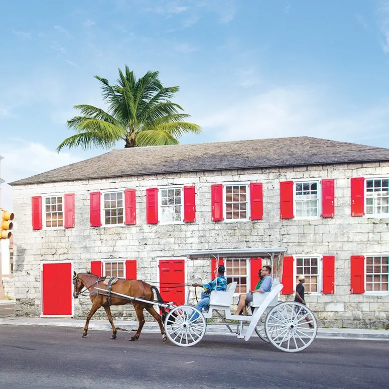 A horse-drawn carriage passing a red-shuttered colonial building in downtown Nassau