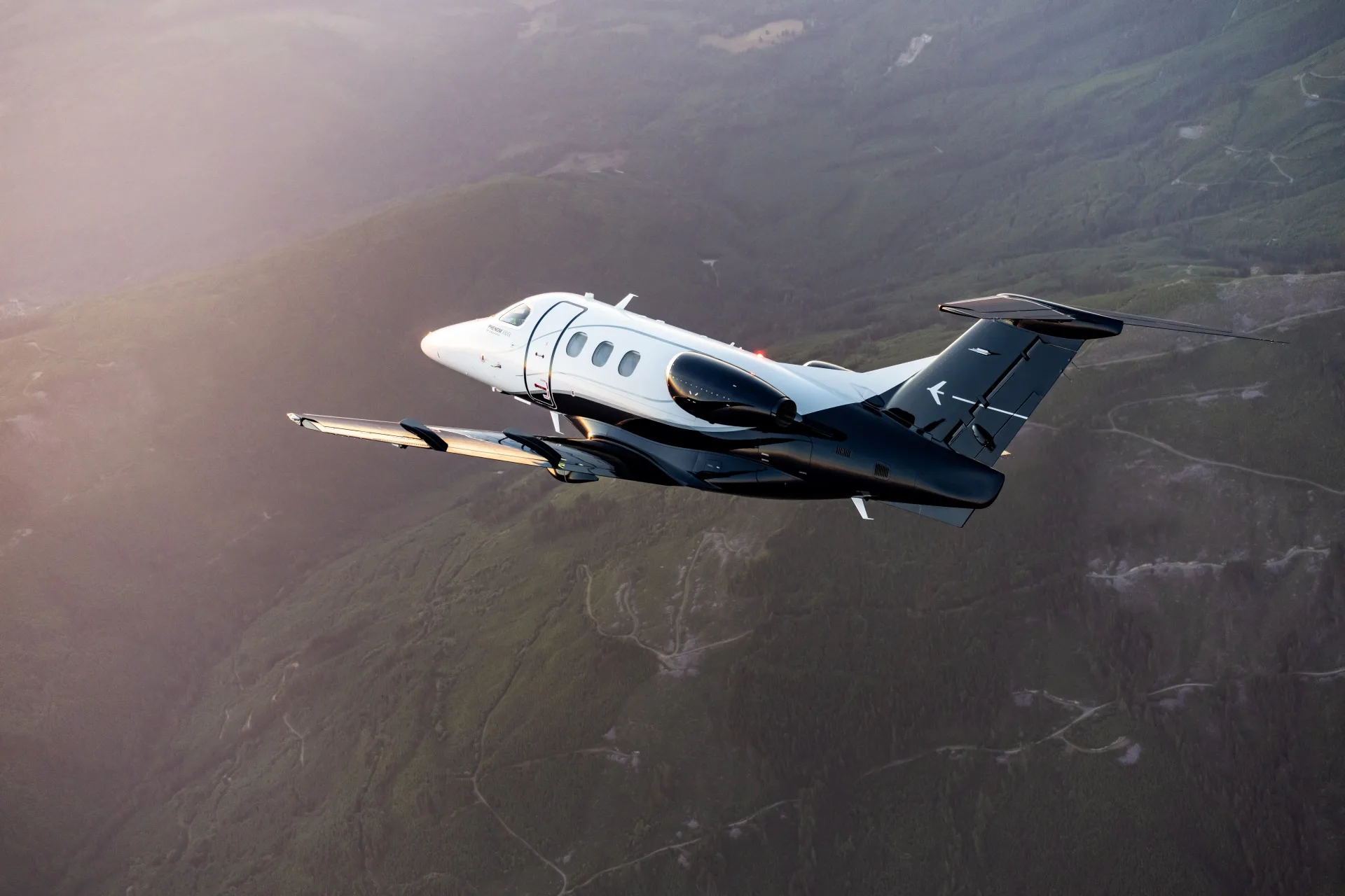 Embraer Phenom 100 in flight over mountains